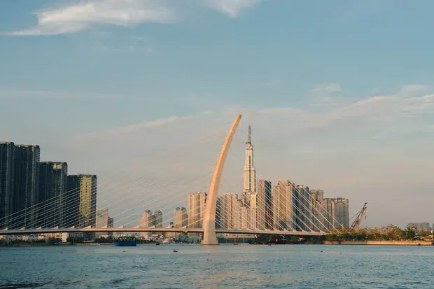 The Ba Son Bridge across the Saigon River at sunset, with the riverside towers and Landmark 81 behind it.