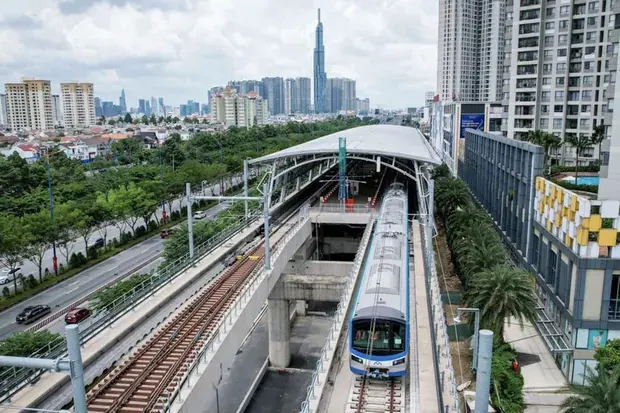 Photograph of a Metro Line 1 train at an elevated station in Ho Chi Minh City, with the city skyline in the distance. The line is in operation.