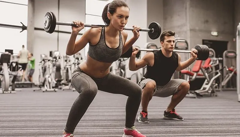Two people training with barbells in a gym